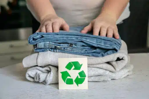 Garment recycling concept. A stack of clothes is on the recycling table. Collection of clothes for recycling.
